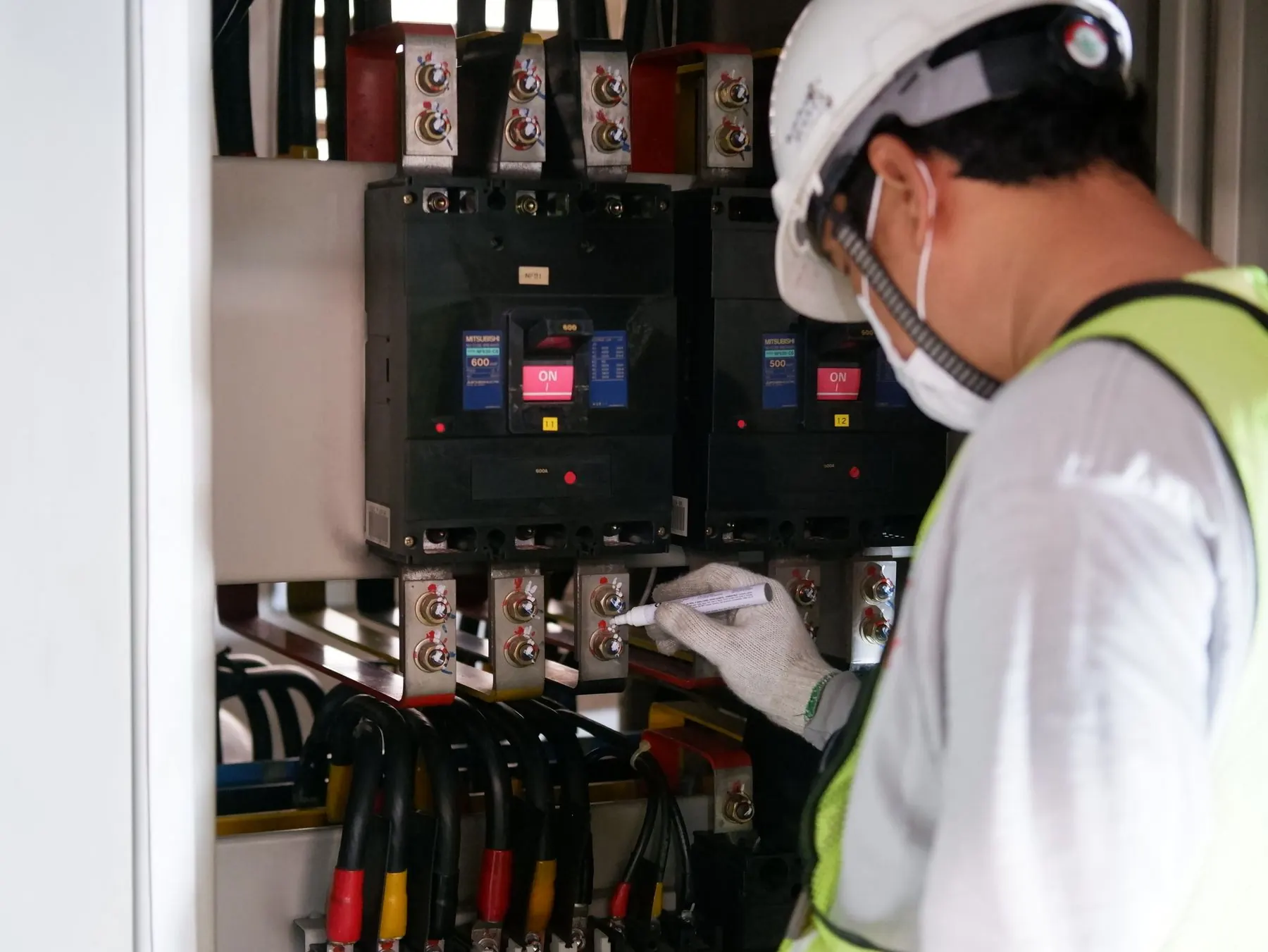 Technician wiring moulded case circuit breakers into a distribution panel