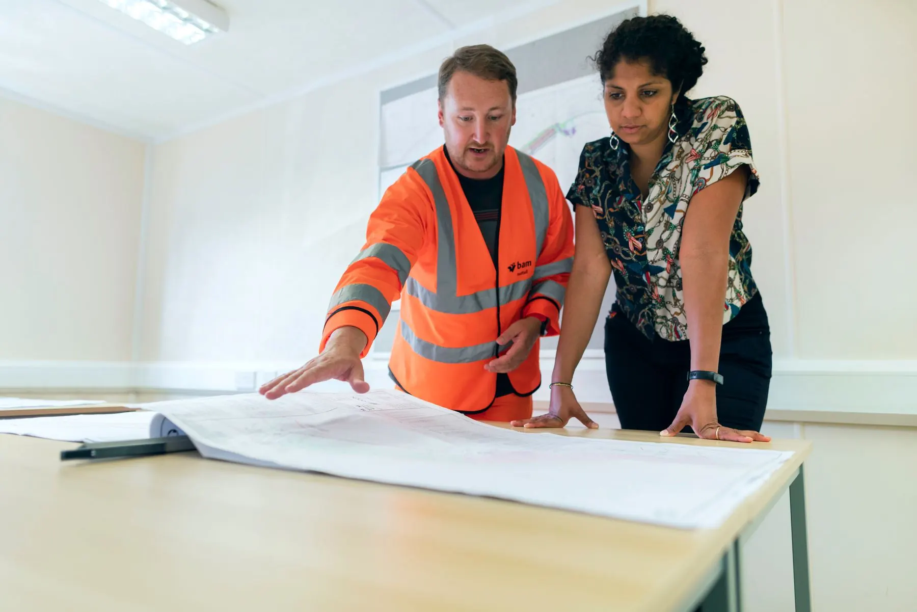 Two engineers reviewing electrical drawings together on site