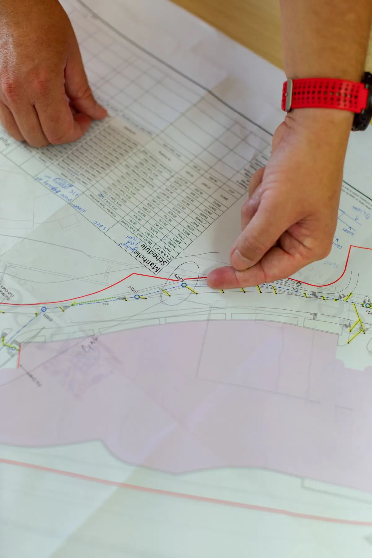 Hands tracing a technical drawing during electrical plan approval