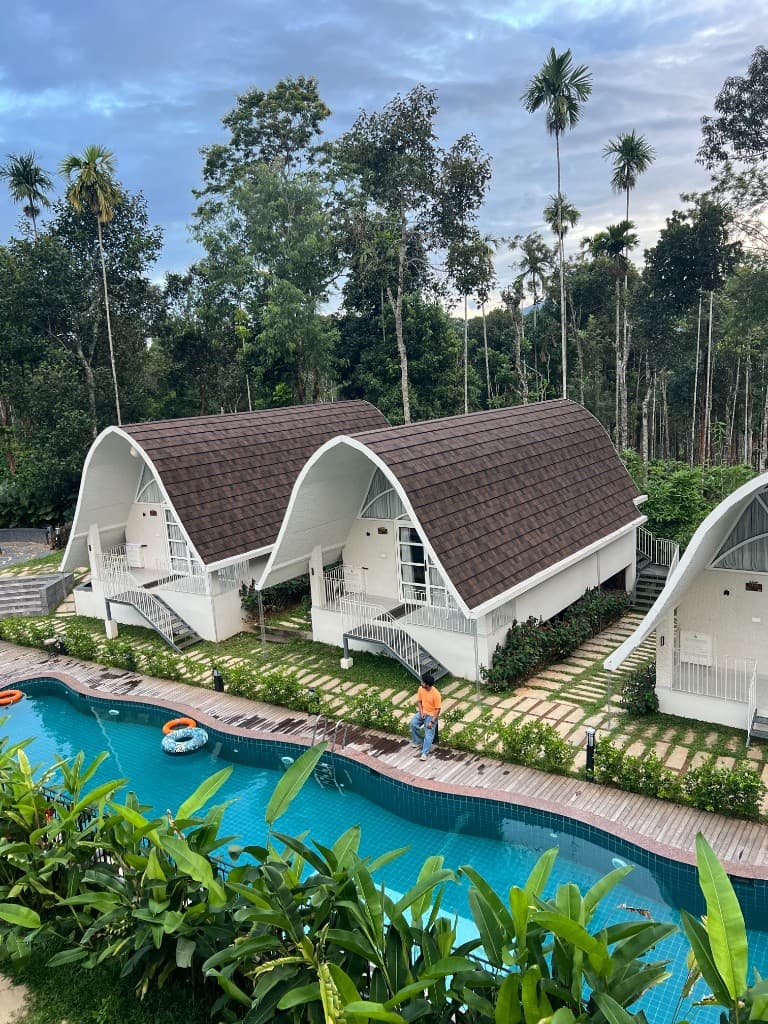 A-frame cottages beside the swimming pool at Golf Valley Resort, Kalpetta, Wayanad